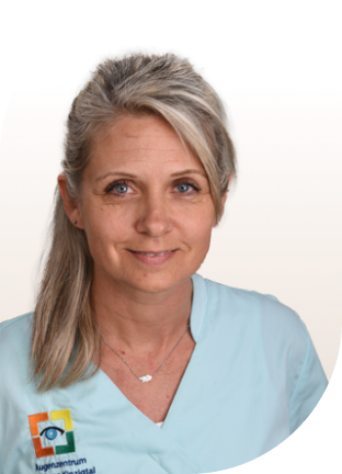 Frau mit hellblonden Haaren im Pferdeschwanz, trägt hellblaues Oberteil mit Logo des Augenzentrums und zwei Ketten mit Anhängern.